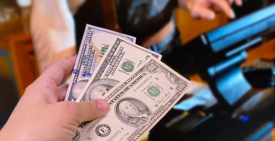 Customer hands cashier three different designs of $100, all are legal tender, regardless of when they were issued.
